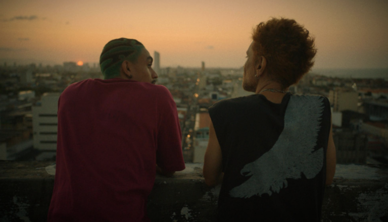 Fotografia, Grupo de jovens observa o centro do Recife ao pôr do sol, representando a juventude conectada à cidade e ao futuro.